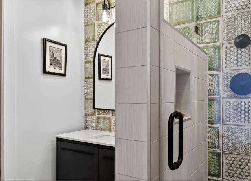 Bathroom detail pairing the vanity wall with the shower niche set into green and blue patterned tile.