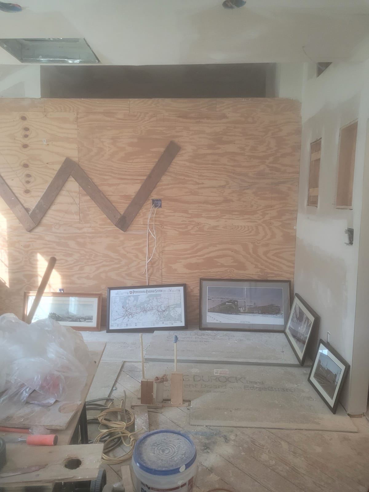 The kitchen under construction, with a plywood subfloor, open framing and materials stacked against the wall.