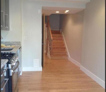 The hallway as found, with a wooden stair, oak floors and a builder-standard kitchen at the left.