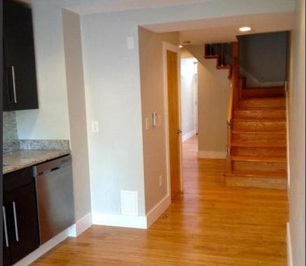 The kitchen passage as found, with dark cabinetry, a stone counter and the stair beyond.