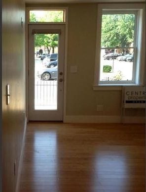The front room as found, looking toward the glazed front door over bare oak floors.